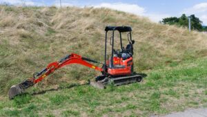 Minibagger mit Planierschild auf einer Wiese