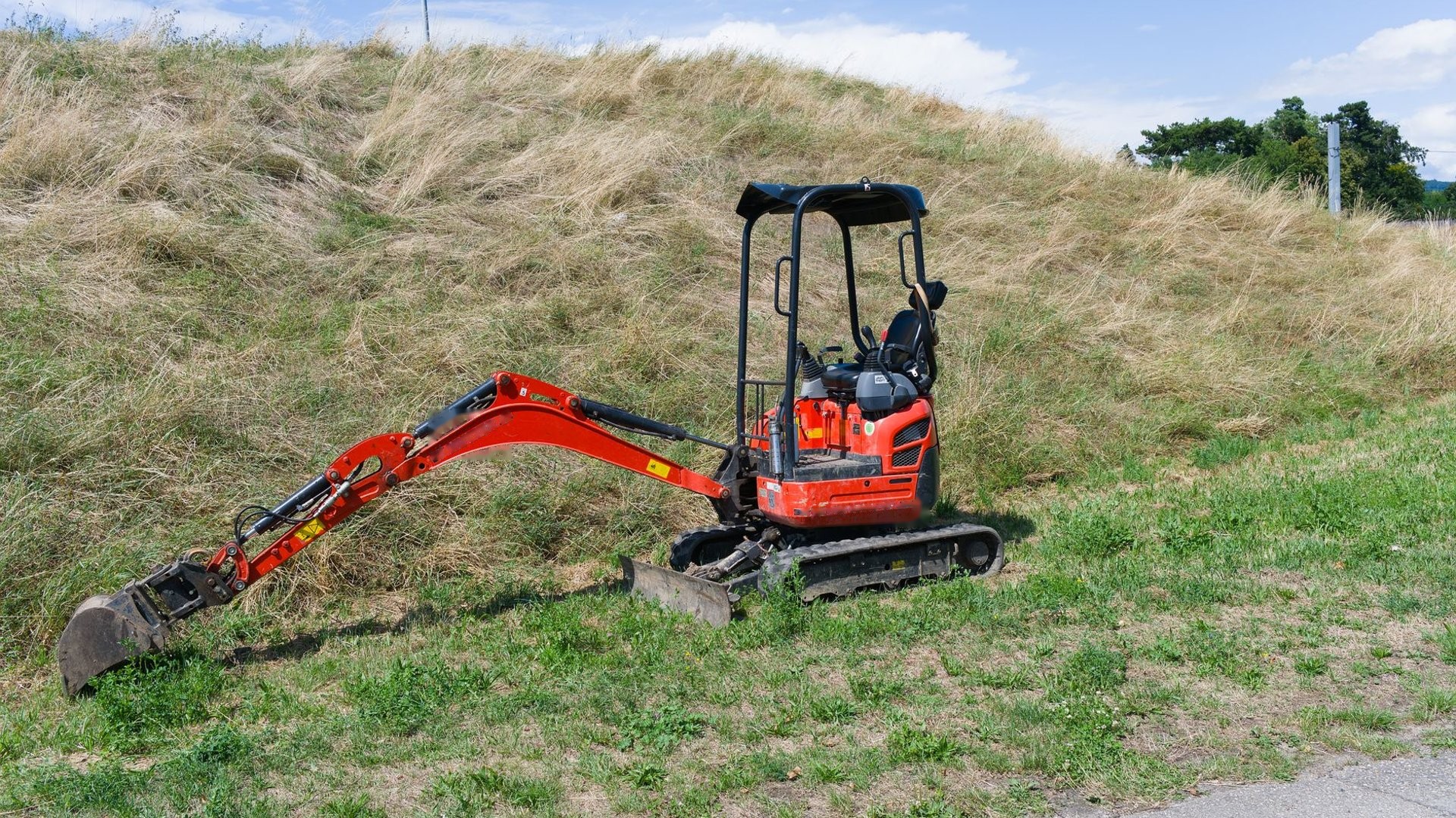Minibagger mit Planierschild auf einer Wiese