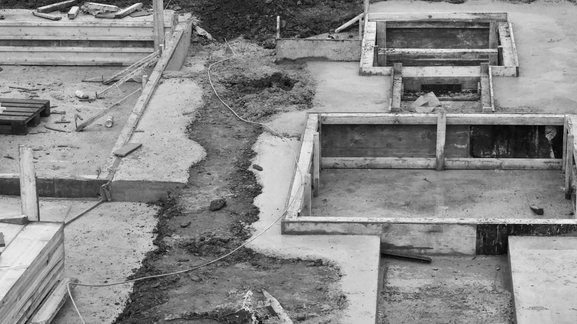 Rohbau-Baustelle mit Schalung und gestapelten Brettern, die Arbeiten stehen still